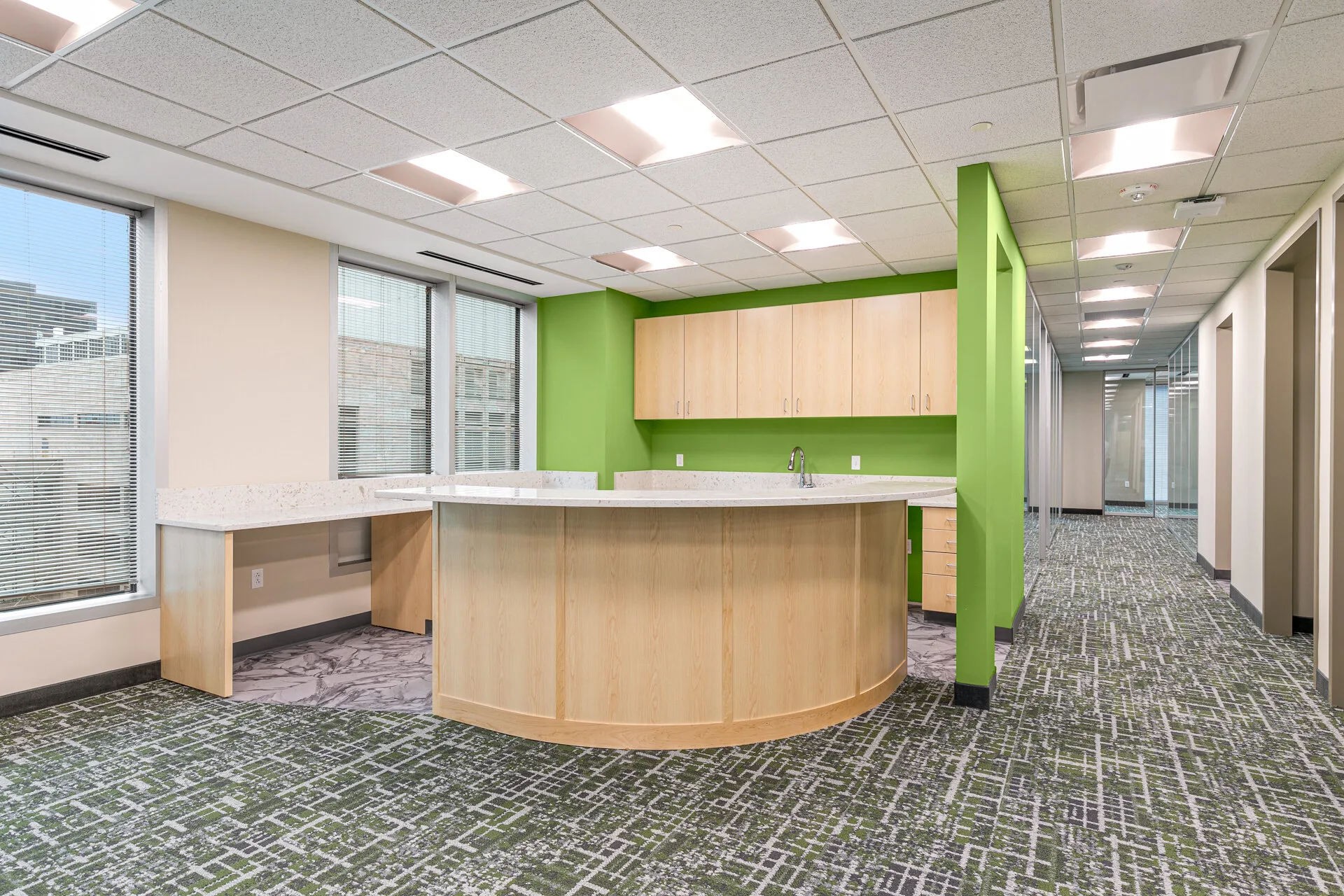 Alternate angle of corporate reception with glass partitions and patterned carpet tile — office build-out by Skoda Construction, Northeast Ohio