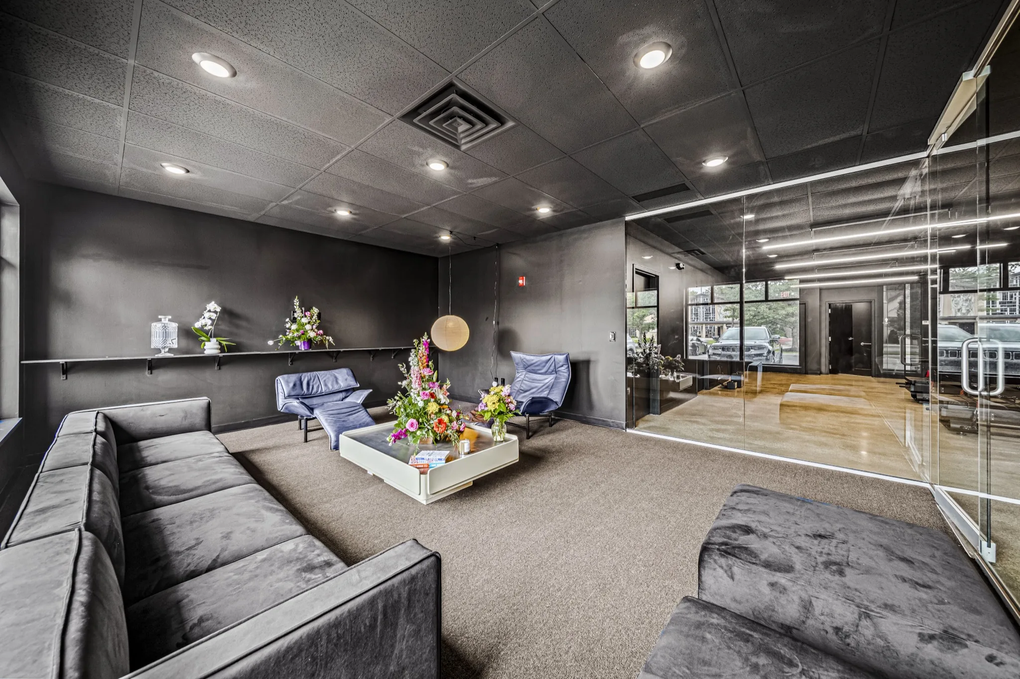 Modern fitness studio lounge with dark walls, designer seating, and glass partition — commercial construction by Skoda Construction, Northeast Ohio