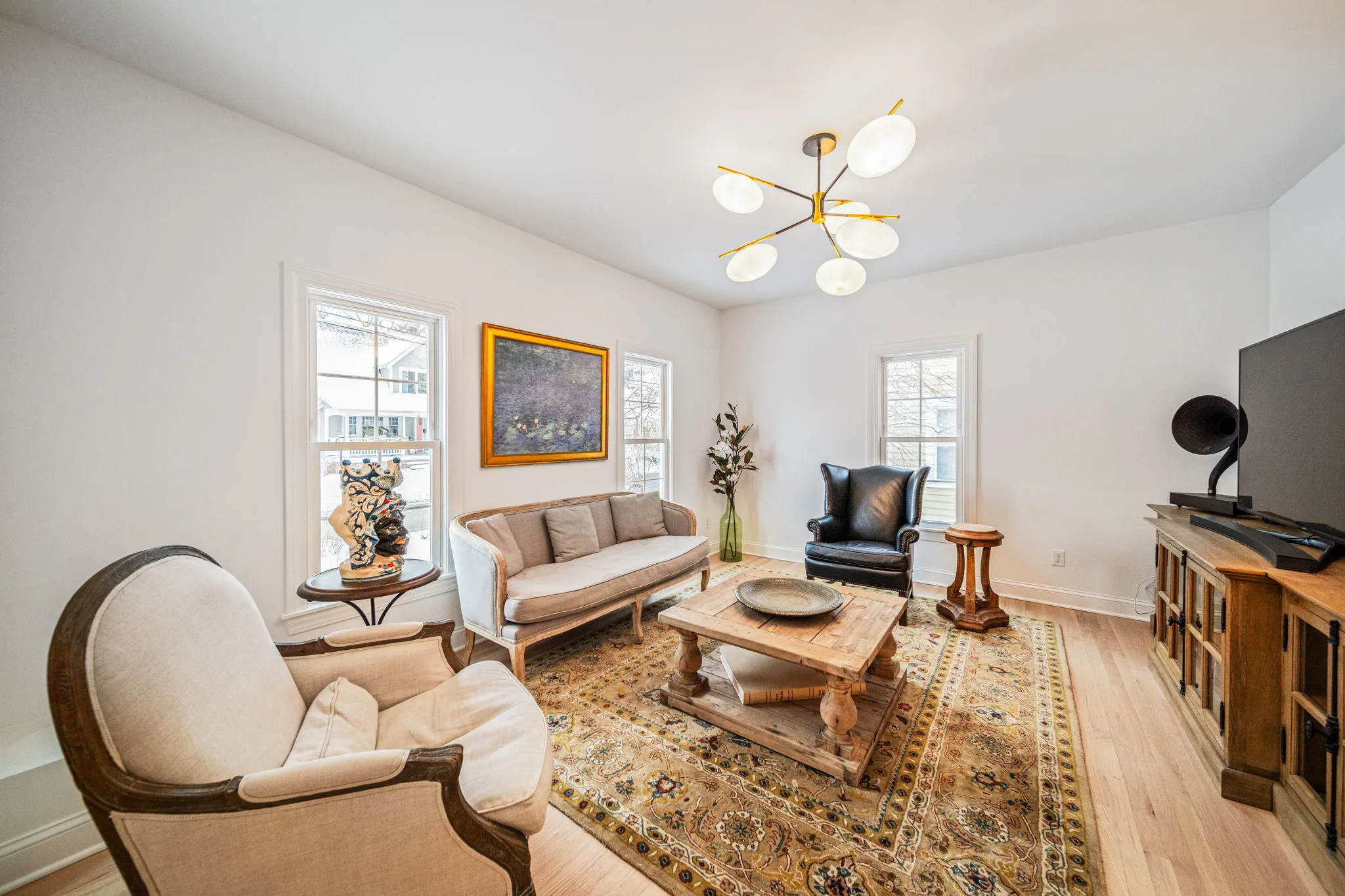 Renovated front parlor with modern sputnik chandelier, hardwood floors, and classic millwork — residential renovation by Skoda Construction, Northeast Ohio
