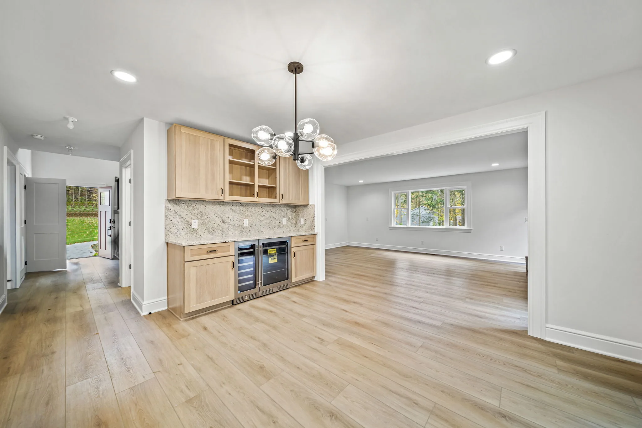 Custom beverage station with sputnik chandelier, dual wine coolers, and natural oak cabinetry — luxury home by Skoda Construction, Northeast Ohio