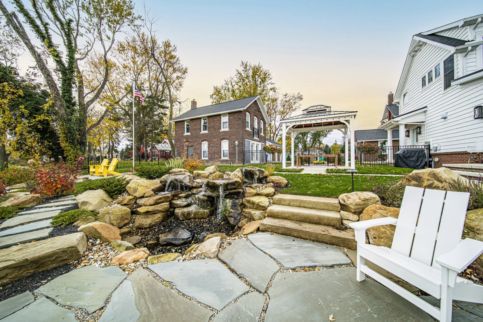 Natural stone waterfall and flagstone patio with Adirondack seating in custom backyard — luxury outdoor living by Skoda Construction, Northeast Ohio