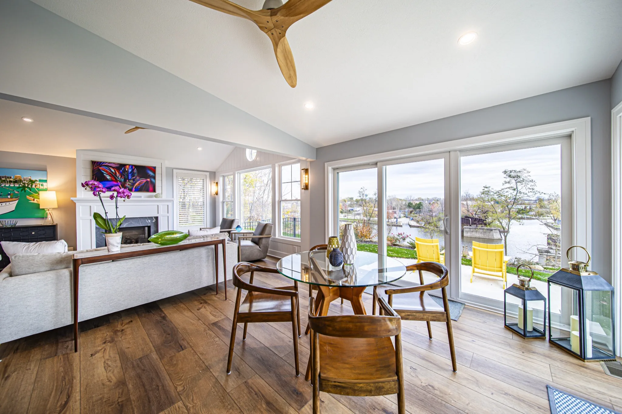 Sun-filled dining area with floor-to-ceiling windows, wood-blade ceiling fan, and waterfront views — custom home by Skoda Construction, Northeast Ohio