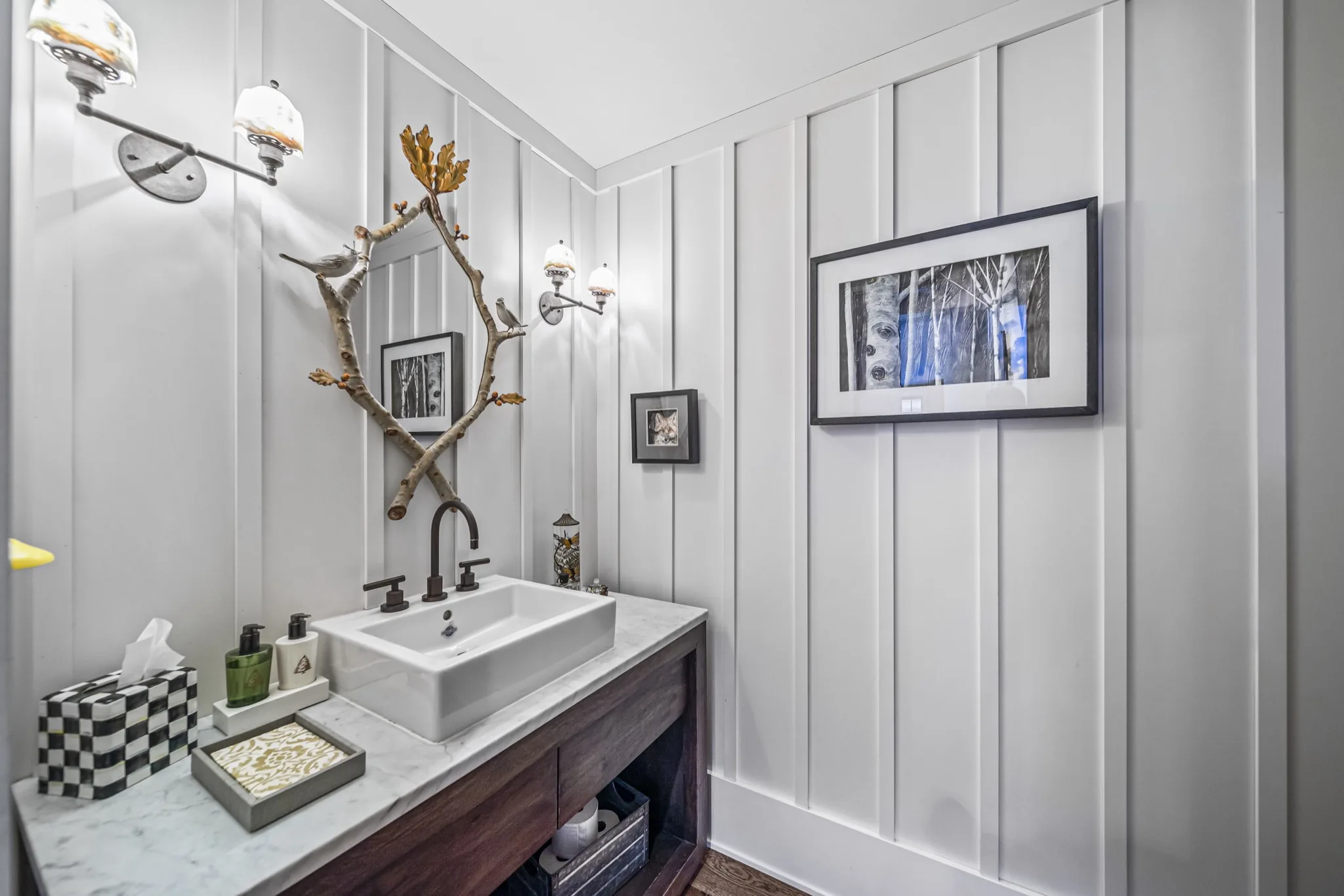 Rustic powder room with board-and-batten walls, vessel sink on reclaimed wood vanity, antler-inspired mirror, and marble countertop — custom farmhouse by Skoda Construction, Northeast Ohio